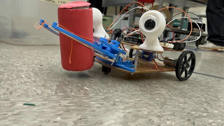 The claw picking up a red soda can slightly above the ground during a test-run.