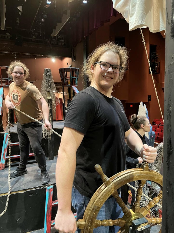Me and my twin brother posing on the ship backstage. I am holding the steering wheel while he pulls on a rope.