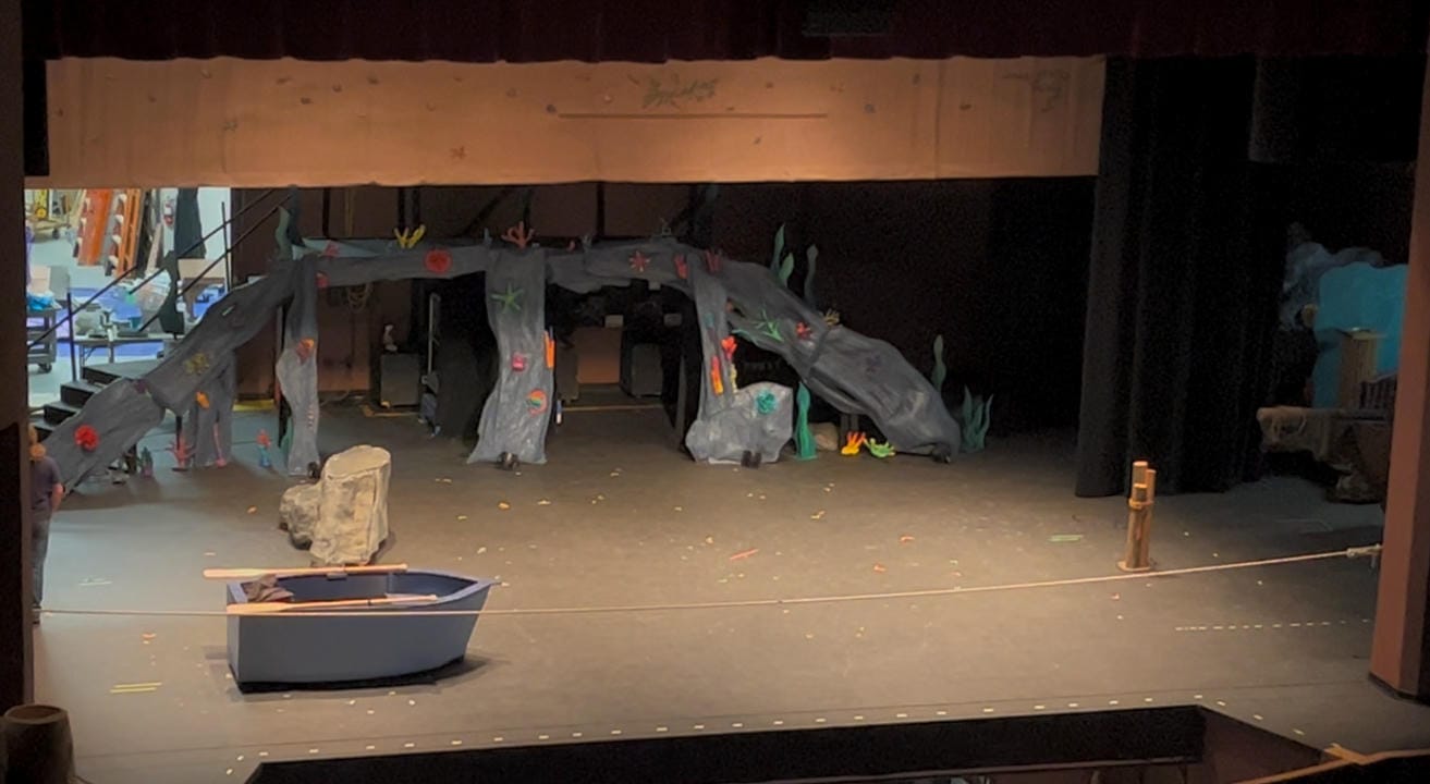 Ariel's row boat on stage with the scene shop behind it.